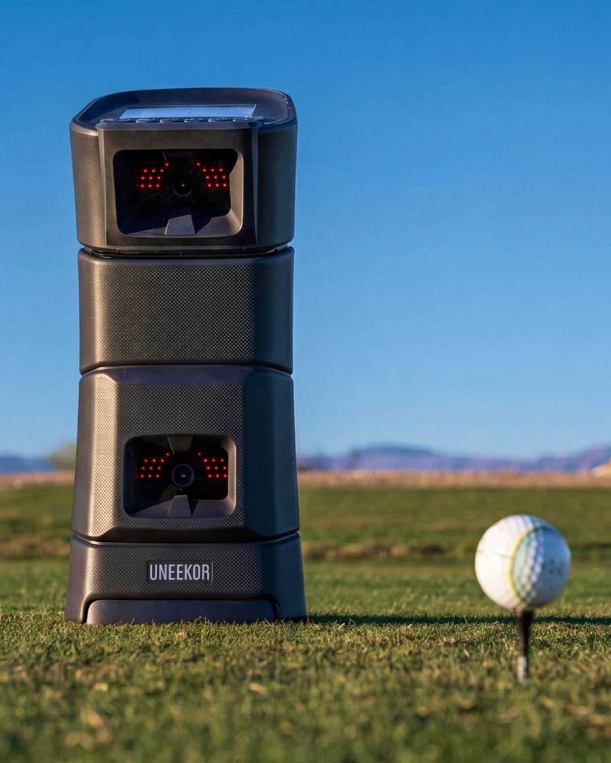 Uneekor EYE MINI positioned beside a golf ball for outdoor practice